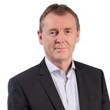 A man in a suit stands confidently against a white background, embodying professionalism and composure.